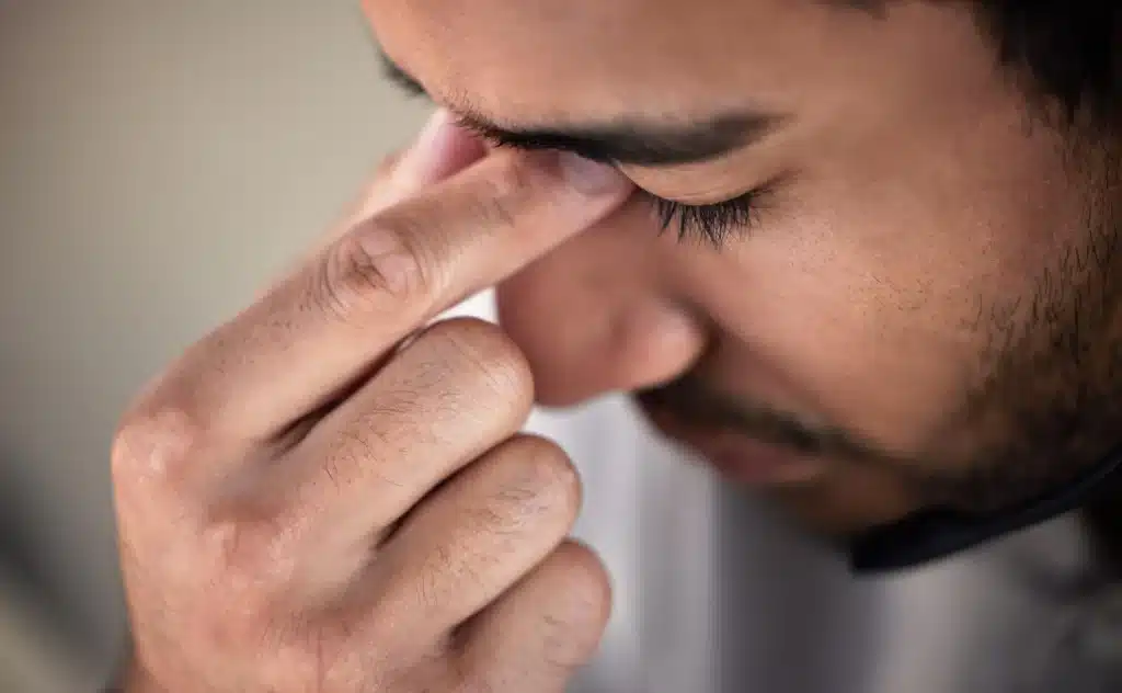 Hombre presionándose la zona entre los ojos con gesto de molestia
